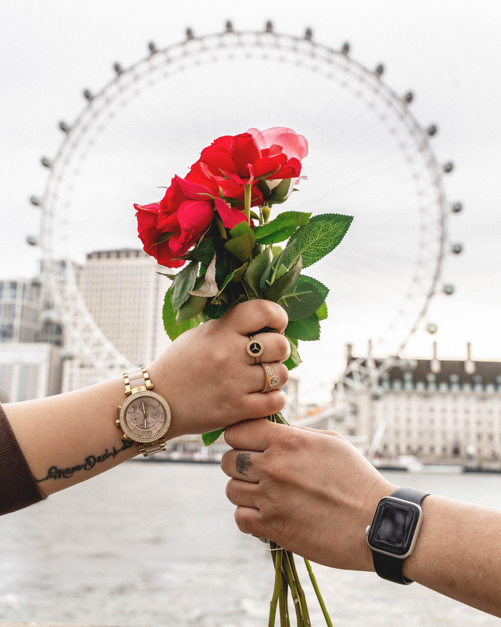 A romantic couple dancing and twirling in front of the iconic Tower Bridge on a rainy London day, professional photography by London Snap.
