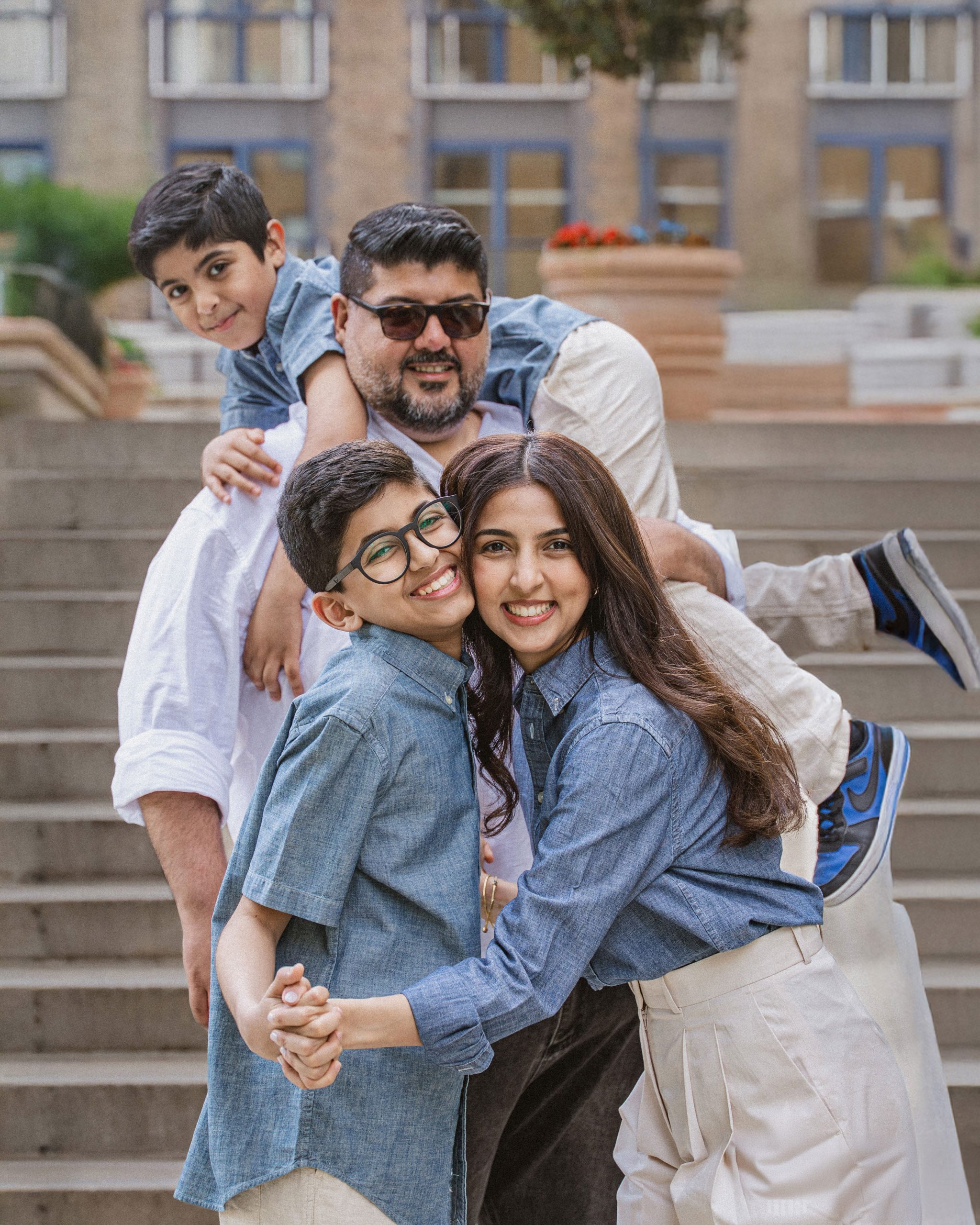 A happy family of four including parents and two young sons smiling and hugging during an outdoor photoshoot in London, captured by London Snap.