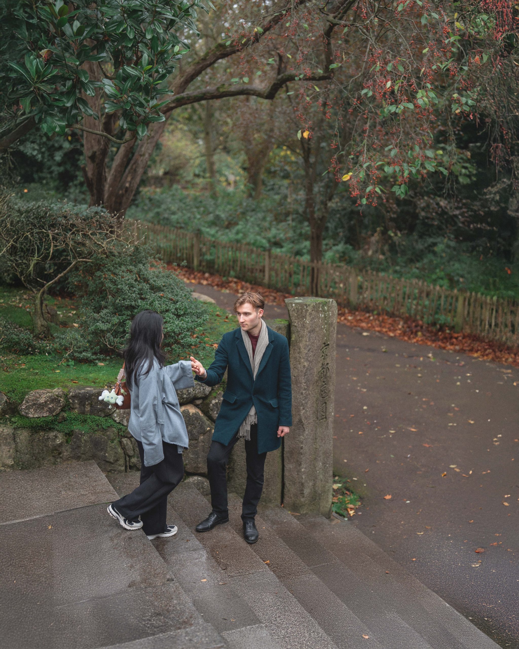 A man holding a woman's hand on stone steps in a quiet London hidden garden, captured by London Snap photography agency.